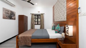 A neatly arranged bedroom with a bed, a wardrobe, a bedside table with a lamp, a ceiling fan, and a window with curtains. - Villa Calangute Phase 4, Near Calangute Beach & Restaurants (Calangute)