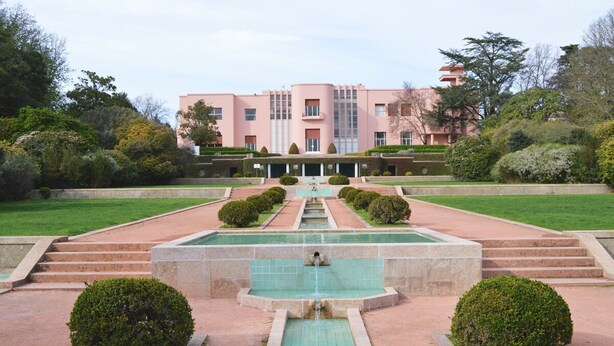 A building with a symmetrical facade, a central water feature, and a well-manicured garden.