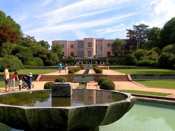 A courtyard with a fountain, steps leading to a building, and well-maintained greenery.