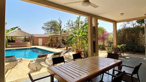 A covered outdoor area with a pool, lounge chairs, and a dining table. - Somone: large air-conditioned villa with swimming pool, 10 people *, between Sea and Lagoon (Unknown)