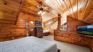 A wooden cabin bedroom with a bed, dresser, and television. - Breathtaking Mtn VIEWS!! Cozy yet spacious peaceful cabin in the mountains! (Sevierville)