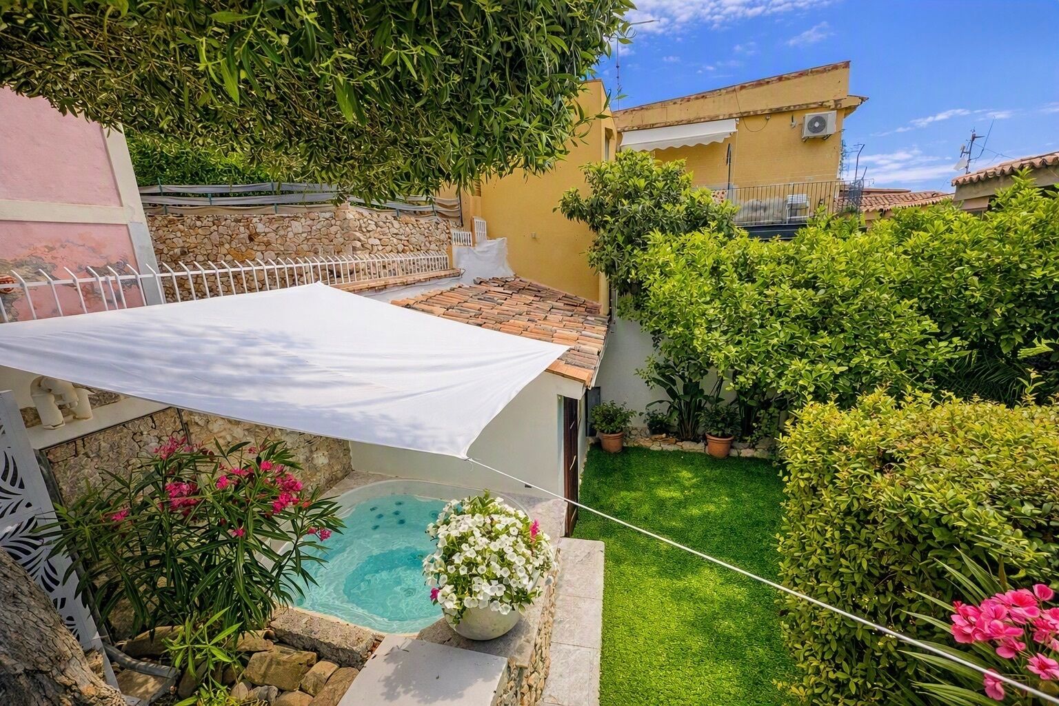 Ein privater Garten mit Swimmingpool, einer weißen Markise und einer Steinmauer.