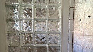 Un baño con ventana de vidrio esmerilado, dispensador de toallas y paredes con azulejos.