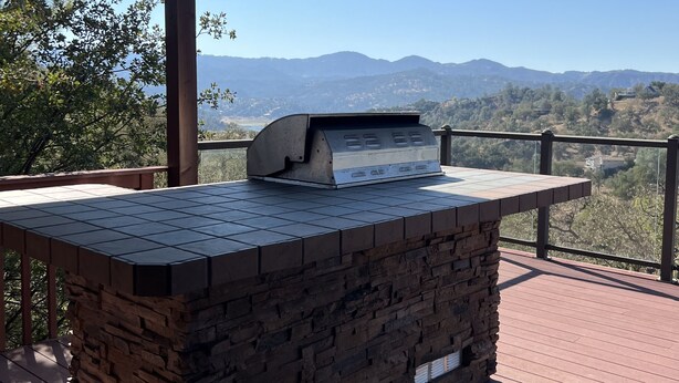 Un área de barbacoa con mostrador de piedra y vista a las montañas.