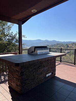 Un espace barbecue doté d’un plan de travail en pierre et offrant une vue sur les montagnes.