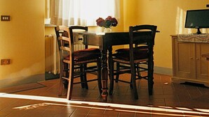 En matplats med ett bord och stolar, en tavla på väggen och ett fönster med gardiner.