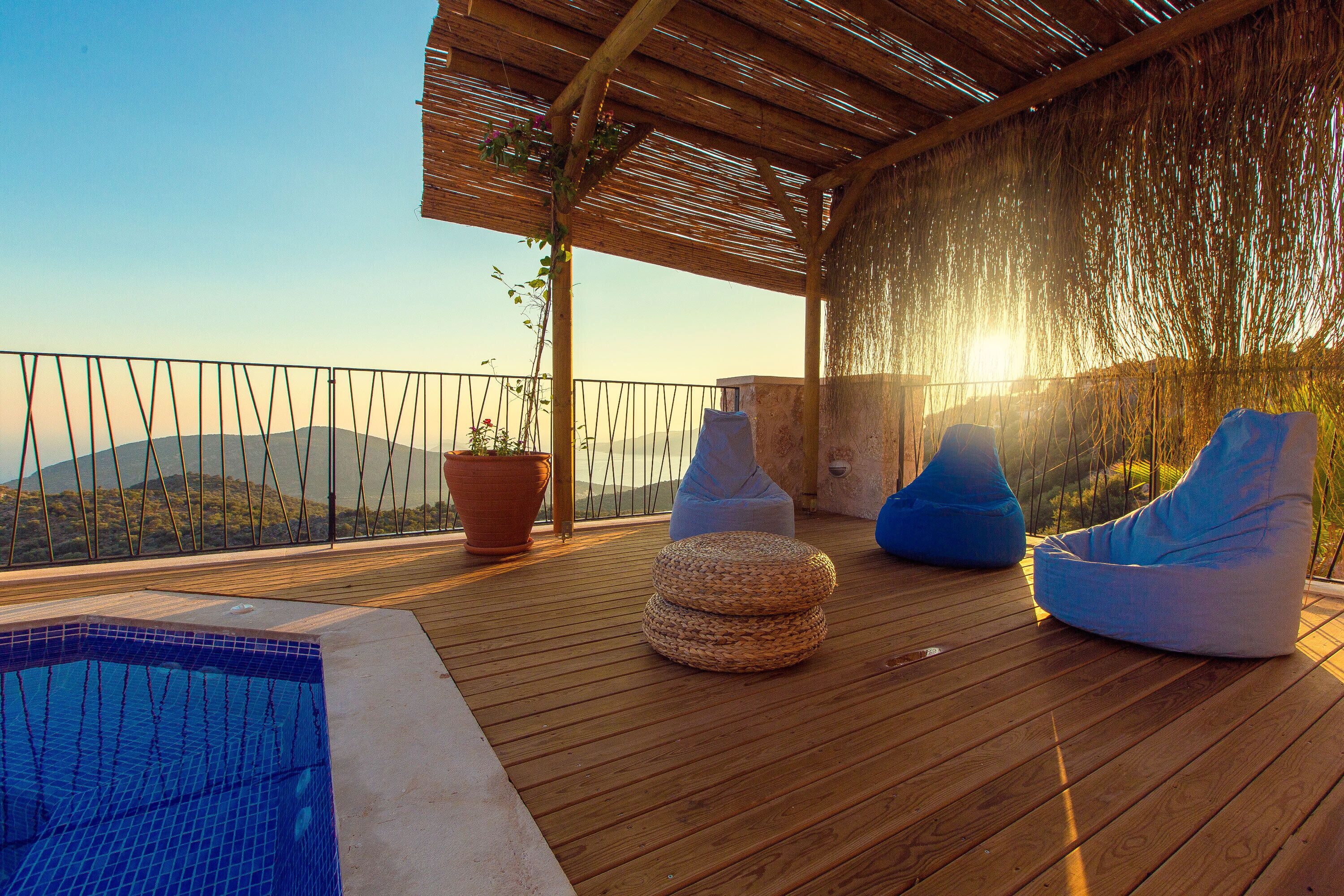 A wooden deck with a pool, blue bean bags, and a view of mountains.