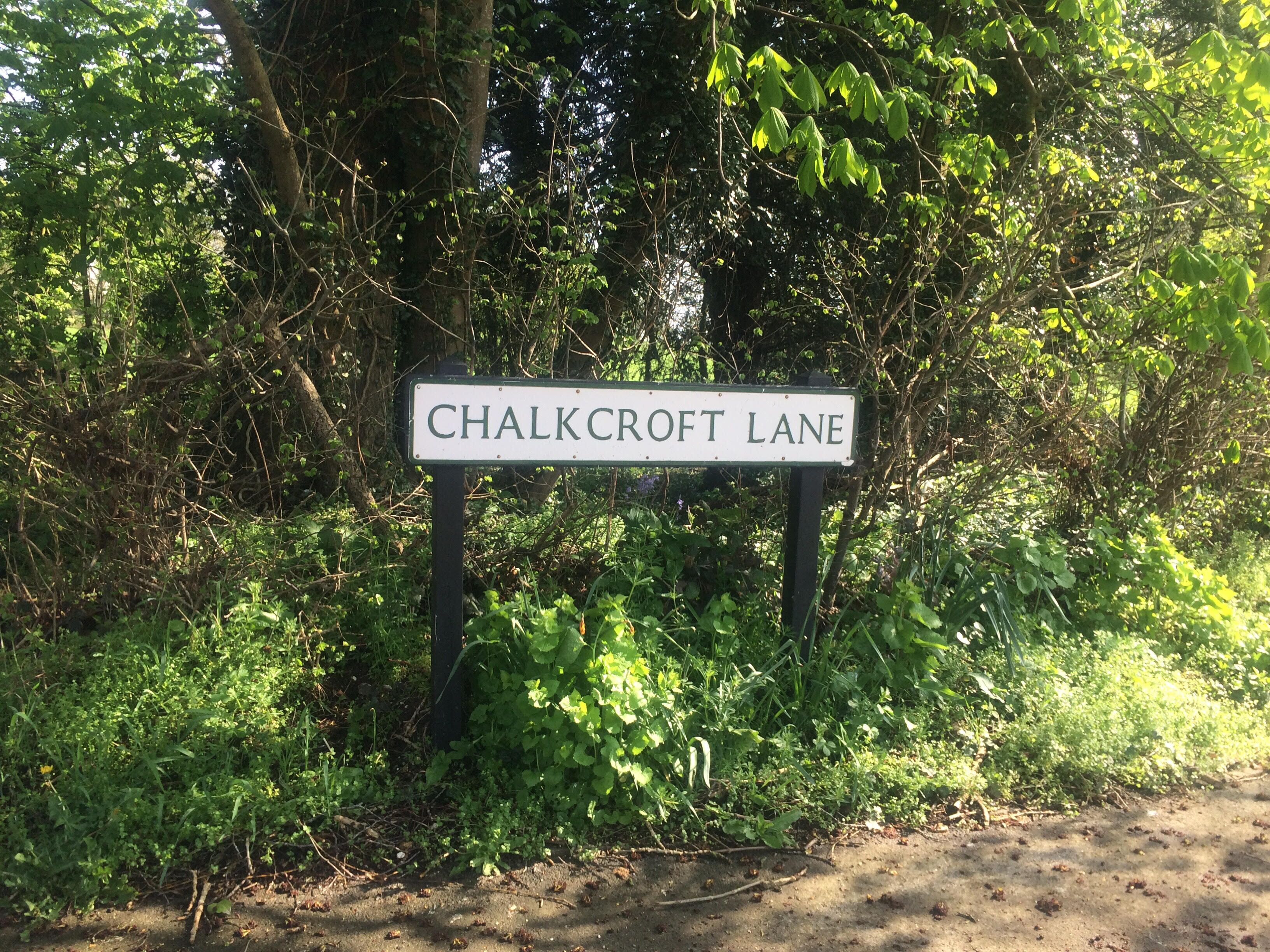 A street sign for Chalkcroft Lane surrounded by dense greenery.