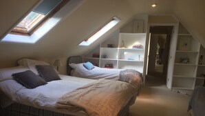 A bedroom with two beds, a skylight, and a built-in bookshelf. - Chalkcroft lodge (Andover)