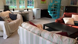 A cozy living room with a striped sofa, a red sofa, and a small black table. There is a window with a view of greenery outside. - Chalkcroft lodge (Andover)