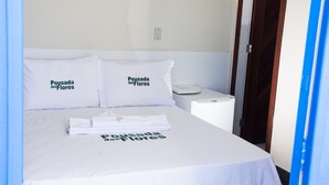 Una habitación de hotel con una cama, dos almohadas con texto, una mesita de noche y un teléfono.