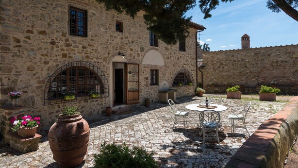 A stone building with a courtyard, outdoor seating, and potted plants.