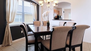 A dining area with a dark wooden table, six chairs, and a chandelier.