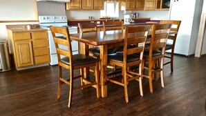 Une cuisine avec des meubles de rangement en bois, une table à manger avec des chaises, une cuisinière et un réfrigérateur.