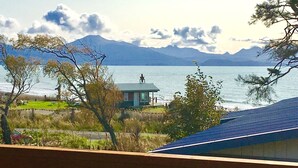 Une vue sur le lac, agrémentée d’un belvédère, avec une montagne en arrière-plan et une maison au toit bleu.