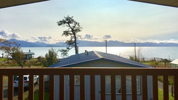 Une vue depuis une véranda couverte donnant sur un lac, avec des montagnes à l’horizon.