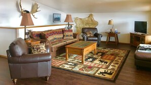 Un salon comprenant un canapé, des fauteuils, une table basse et un tapis à motifs animaliers.
