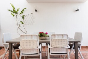 A dining area with a table and six chairs, a decorative plant, and a wall-mounted light fixture.