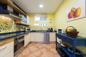 A compact kitchen with a tiled backsplash, stainless steel appliances, and a blue countertop.