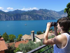 A person taking a photograph of a lake with mountains in the background. - balcony overlooking the lake, wifi, pool, parking (Malcesine)