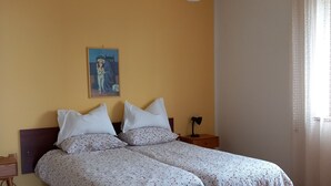 A double bed with floral bedding, a nightstand, a lamp, and a painting on the wall.