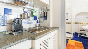 A kitchen with a granite countertop, white cabinets, and blue and white patterned tiles. - M'Illumino d'Immenso Studio with sea view (Praiano)