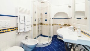 A bathroom with a glass-enclosed shower, a bidet, a sink with a mirror, and a towel rack. - M'Illumino d'Immenso Studio with sea view (Praiano)