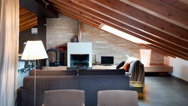 A modern loft with exposed wooden beams, a brick wall, a fireplace, and a large window. - Sant Agostino Loft in historical city center (Catania)