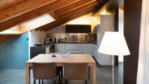 A modern kitchen with wooden beams, a dining table, and chairs. - Sant Agostino Loft in historical city center (Catania)