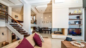 Ein geräumiger Wohnbereich mit Treppe, Essbereich und Fernseher.