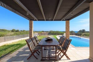 Ein überdachter Außenbereich mit Pool, Tisch und Stühlen sowie Blick auf die Landschaft.