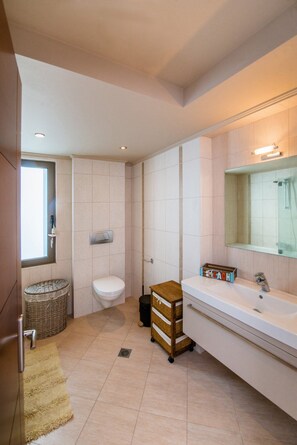 Ein modernes Badezimmer mit Toilette, Bidet und einem großen Spiegel über dem Waschbecken.