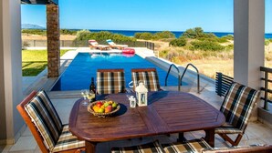 Ein überdachter Essbereich mit Pool und Meerblick.