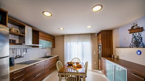 Eine moderne Küche mit Holzschränken, einem Esstisch mit Stühlen und einem Kühlschrank.