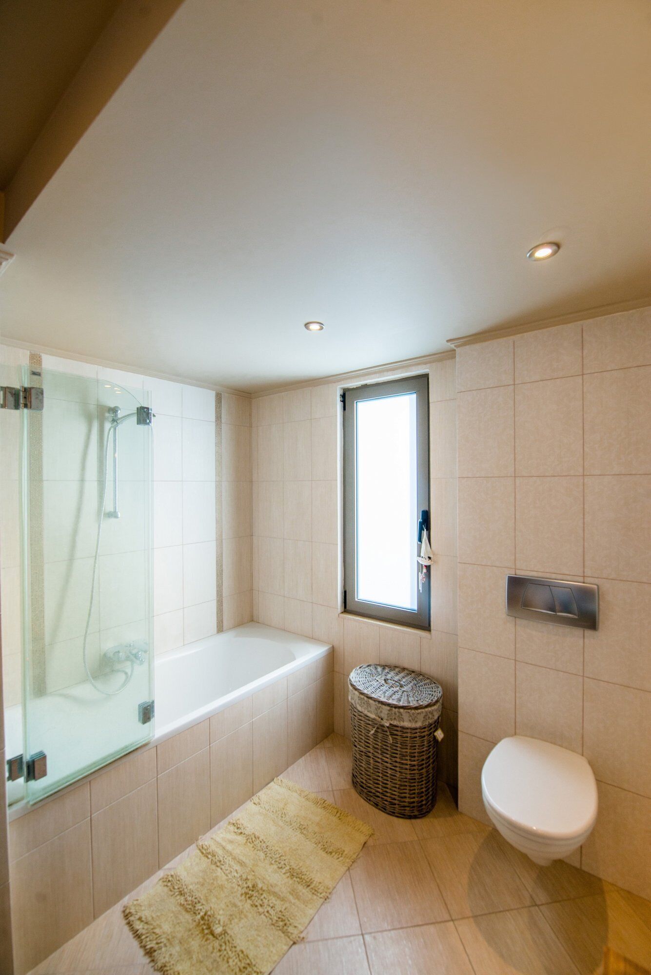 Une salle de bain avec une douche à parois de verre, une baignoire, des toilettes et un panier en osier.