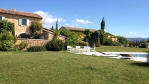 A stone house with a tiled roof, a swimming pool, and a grassy lawn with outdoor furniture. - Les Mûriers: 55m2 gite for 2/4 people in a quiet location overlooking the Luberon and vineyards (Gargas)
