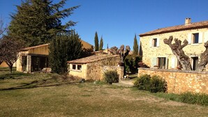 A rustic stone building with a tiled roof, surrounded by a grassy area and trees. - Les Mûriers: 55m2 gite for 2/4 people in a quiet location overlooking the Luberon and vineyards (Gargas)