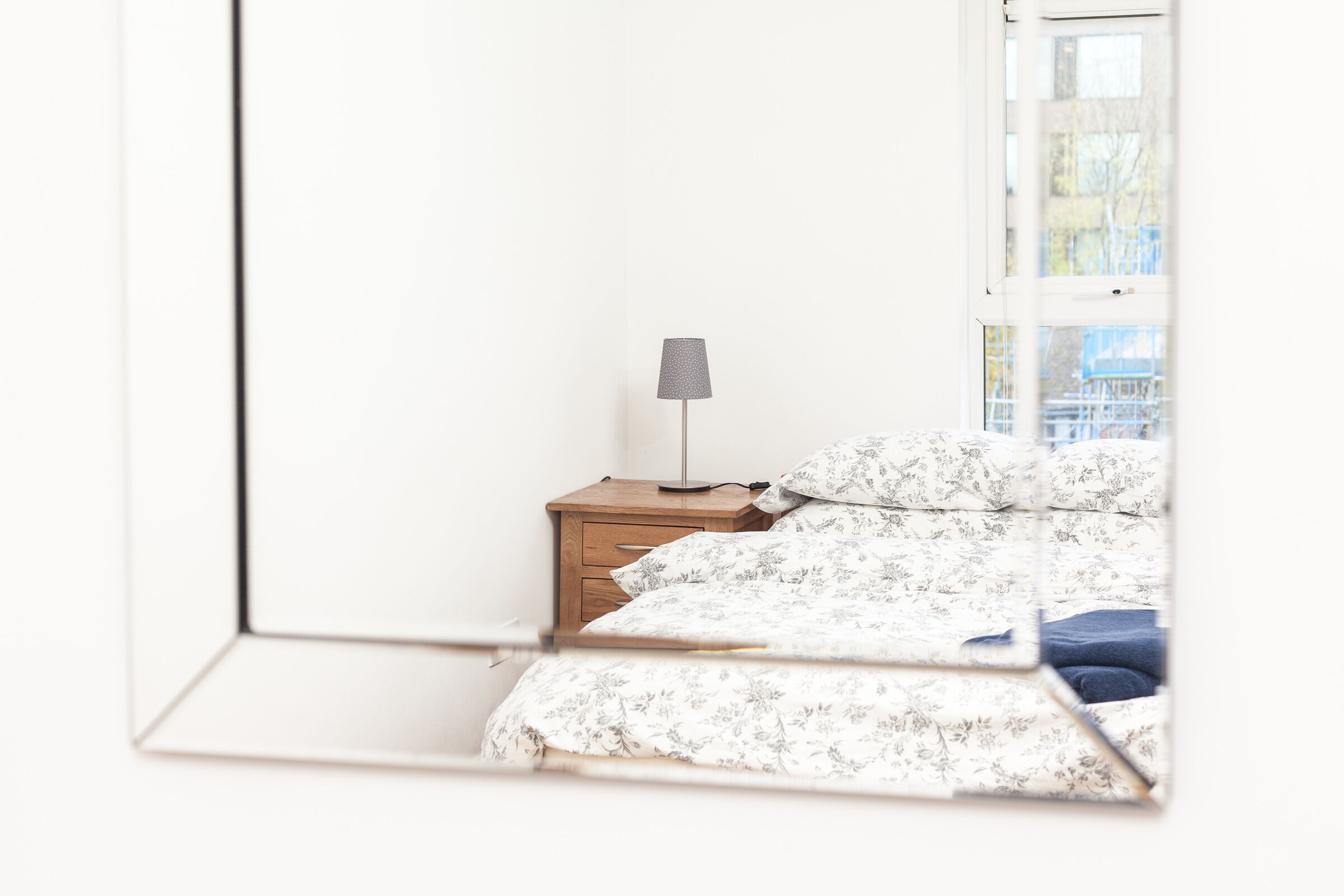 Une chambre à coucher avec un lit, une table de chevet et une lampe.