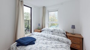 Une chambre à coucher avec un lit, une table de chevet, une lampe et une fenêtre.