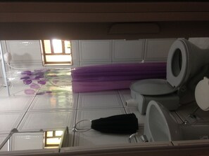 Une salle de bain avec des toilettes, un lavabo et une fenêtre équipée de stores.