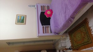 A room with a bed, a small table, a chair, a picture on the wall, and a rug. - Recanto José Augusto (Mairiporã)