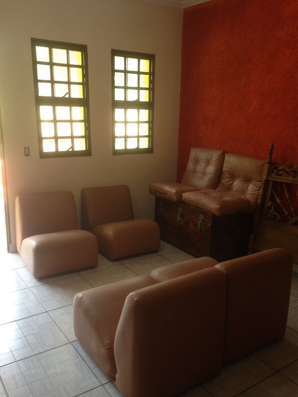 A room with two windows, a red wall, and a brown leather sofa. - Recanto José Augusto (Mairiporã)