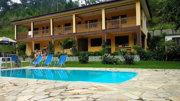 A hotel with a swimming pool, outdoor seating, and a balcony. - Recanto José Augusto (Mairiporã)