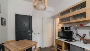Une cuisine compacte avec une table en bois, un four à micro-ondes et une machine à café.