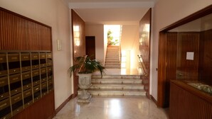 Un hall d’hôtel avec un comptoir d’accueil, un escalier menant à un autre étage et une plante en pot.