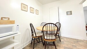 A dining area with a round table, four wooden chairs, a white microwave, and a ceiling fan. - 6649 2W | Central St. Louis Beauty (St. Louis)