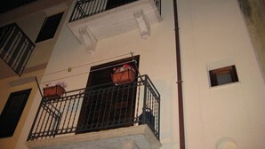 Un immeuble à plusieurs étages doté de balcons, chacun ayant une petite fenêtre et un pot de fleurs.