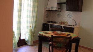 Une cuisine compacte avec un coin repas, comprenant une table recouverte d’une nappe, des chaises, une cuisinière et un évier.