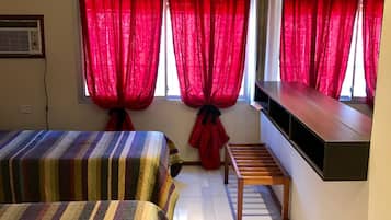 A hotel room with two beds, a TV mounted on the wall, and a small wooden table.
