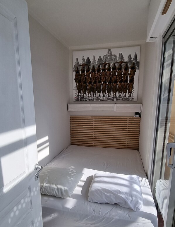 A bedroom with a bed, a window with a decorative metal sculpture, and a wooden headboard. - Nice center: two-room apartment with bedroom, terrace, wifi, internet, air cond. (Nice)